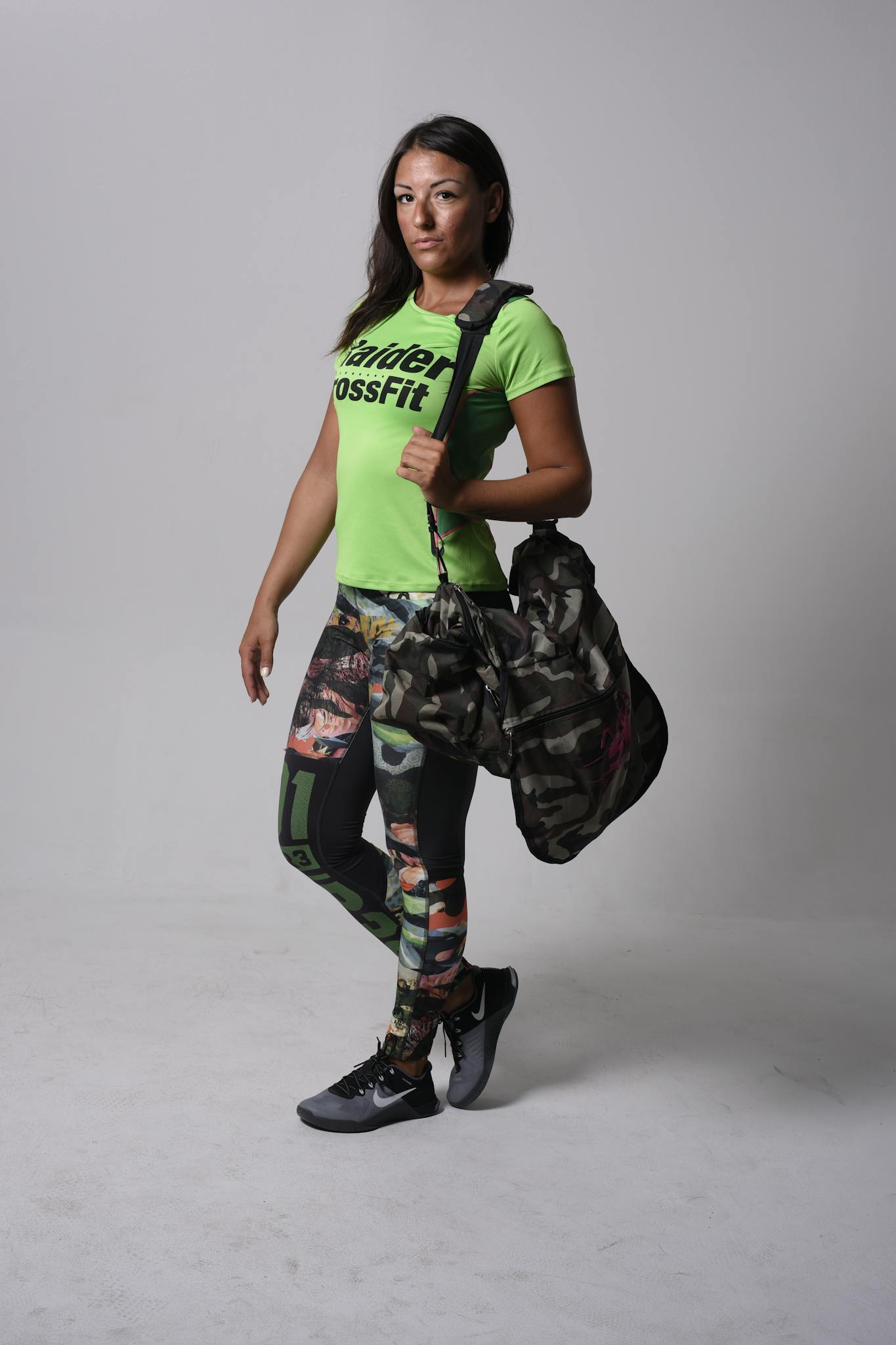 A confident woman poses with gym gear in vibrant workout clothes, ready for fitness.