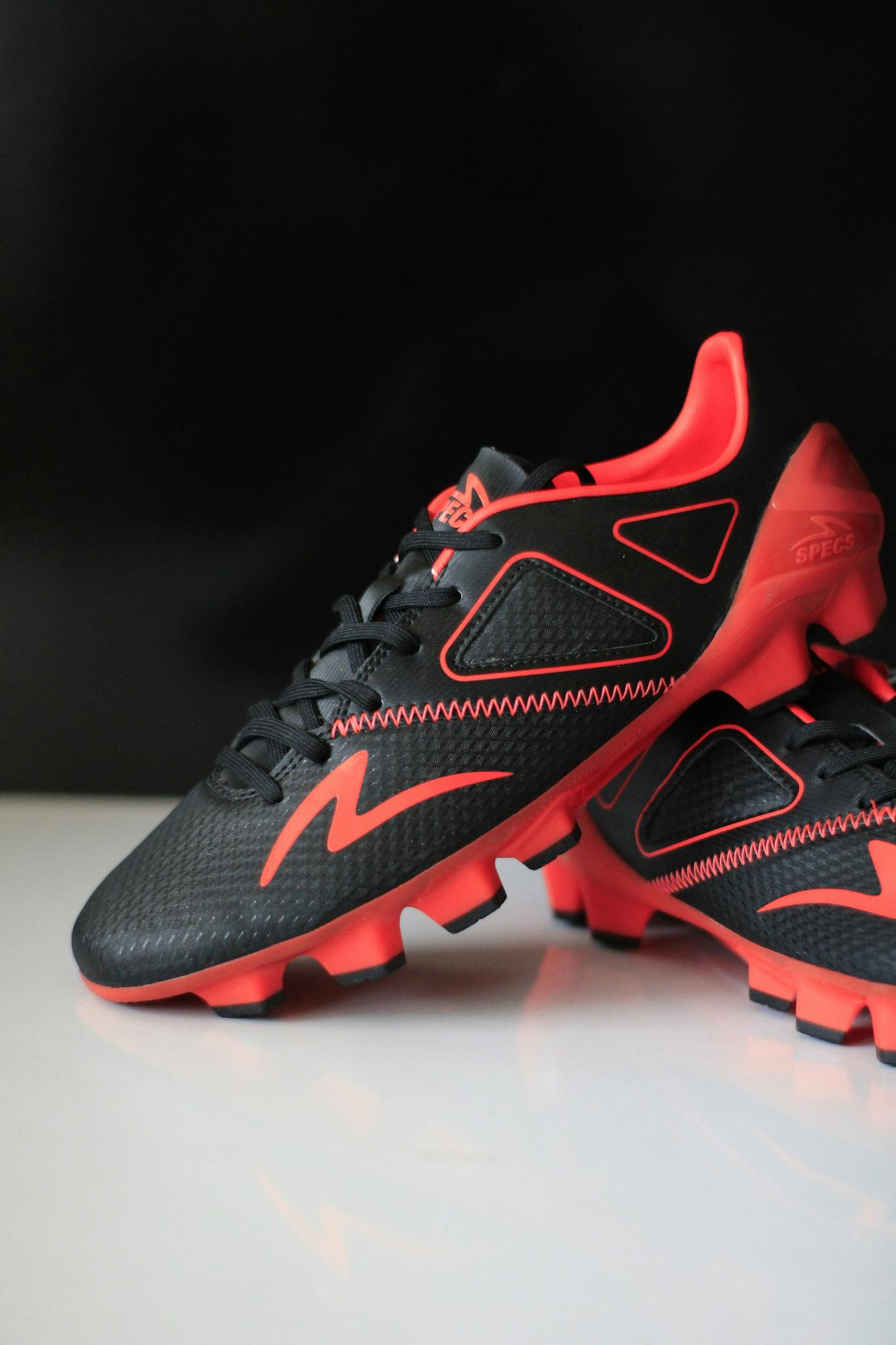 Close-up of stylish red and black soccer cleats on a white surface.