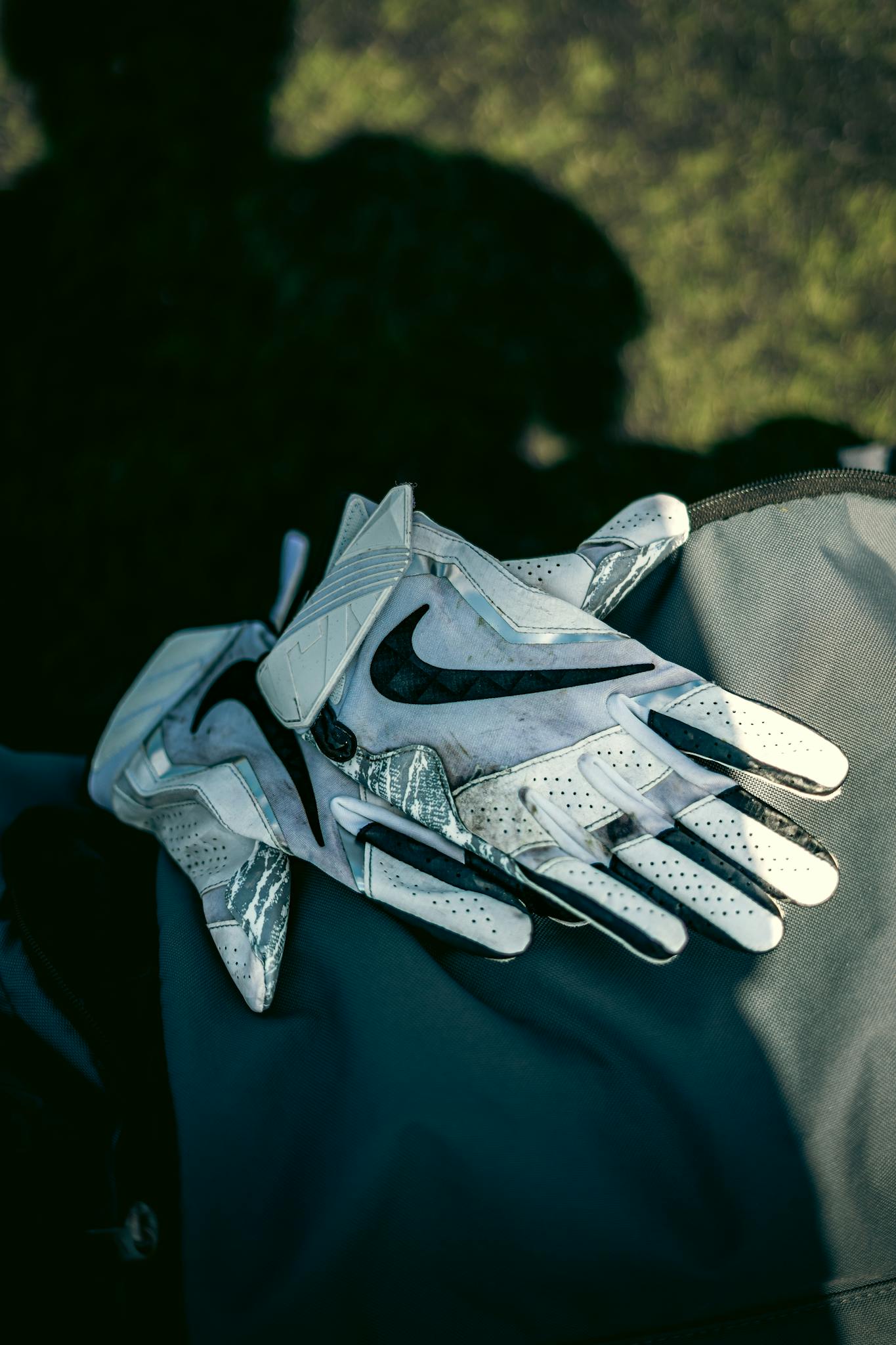 Detailed shot of white sports gloves resting on a bag in natural light.
