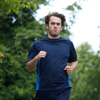 Athletic young man jogging outdoors in forest